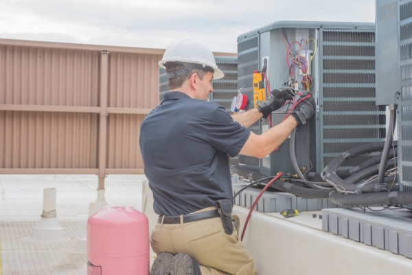 HVAC technician checking refrigerant leaks in an air conditioner