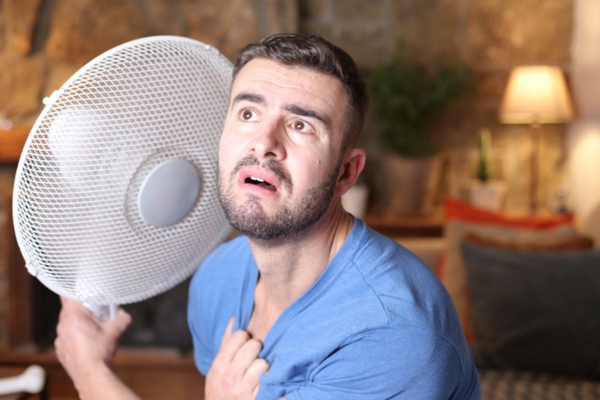 man in front of home fan feeling warm due to air conditioning not working properly